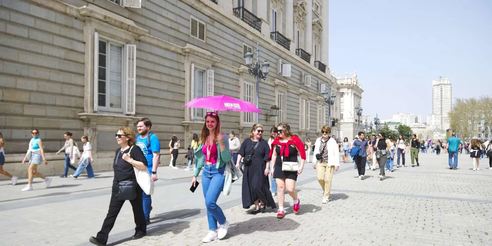 Tour group gathering beneath a pink umbrella