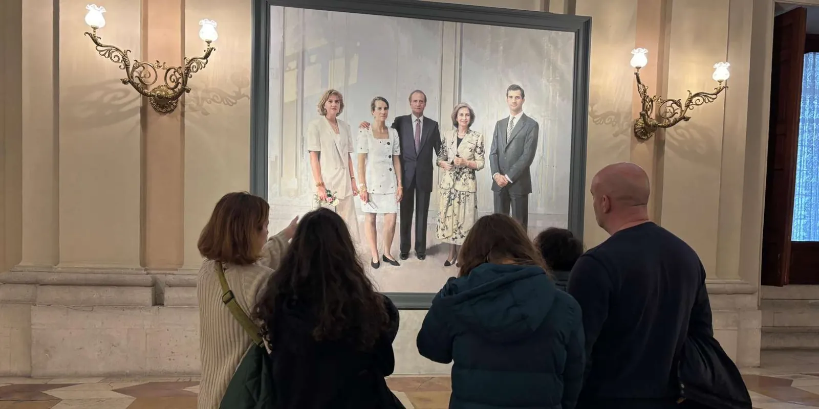 Visitors listening beside a painted royal portrait