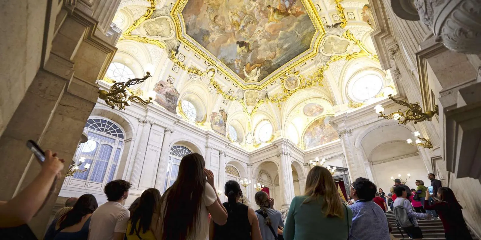 Visitors looking toward a decorated palace ceiling